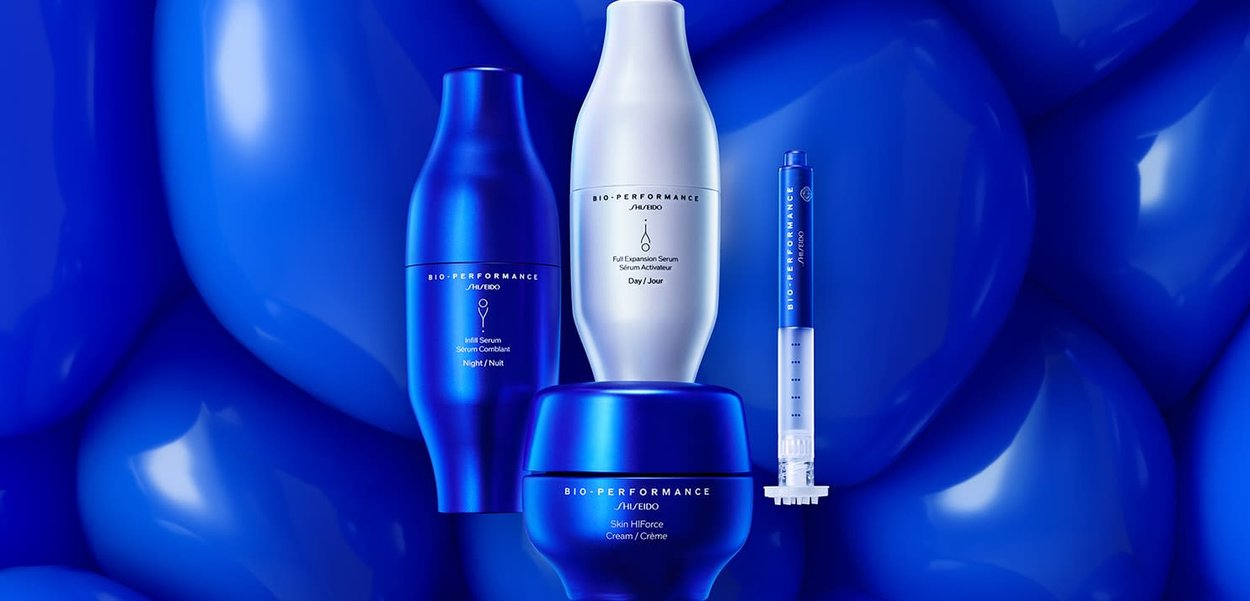 Quatre produits de soin de la peau Shiseido : des bouteilles bleues élégantes avec des textures lisses, des formes variées et des accents argentés, le tout sur un fond de ballon bleu.