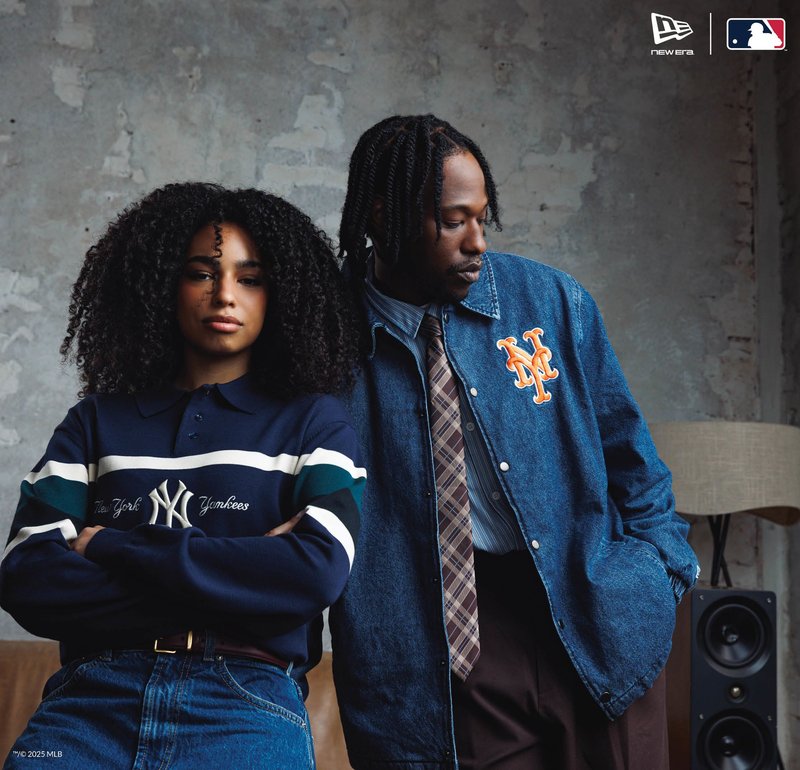 Due persone posano al chiuso; una indossa un maglione dei New York Yankees, l'altra una giacca di jeans con il logo dei New York Mets e una cravatta a fantasia.