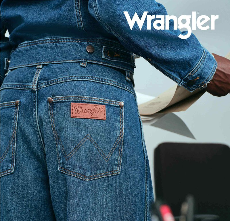 Jeansjakke i mørkeblå med et brunt lærmerke med "Wrangler"-logo, detaljer i sølvfarget metall og særegne sømmer på lommene.