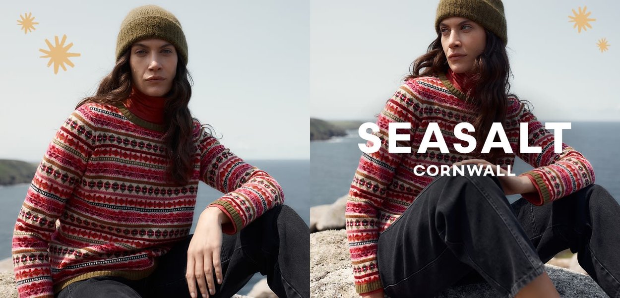 Maglione lavorato a maglia con un motivo multicolore che include rosa, verde e nero. Abbinato a un berretto verde e completato da pantaloni scuri.