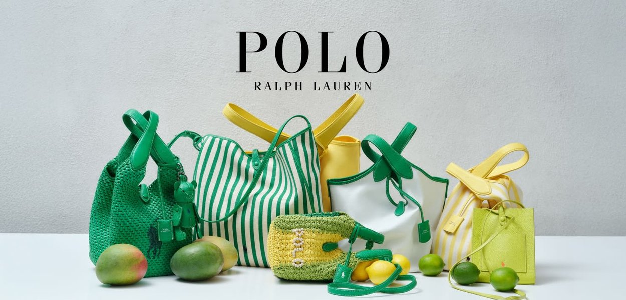 Bolsos y accesorios Polo Ralph Lauren en verde y amarillo dispuestos junto a mangos y limones sobre una superficie blanca.