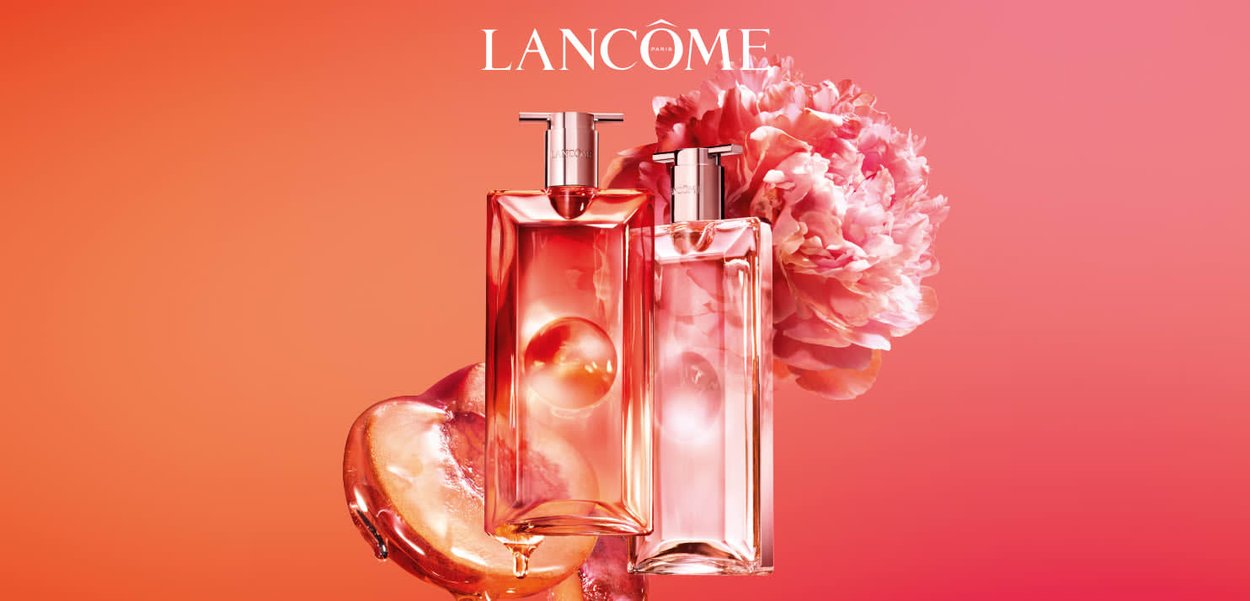 Due flaconi di profumo Lancôme con sfumature rosa e pompe metalliche, un grande fiore di peonia rosa e una pesca luminosa su uno sfondo a gradiente rosa.