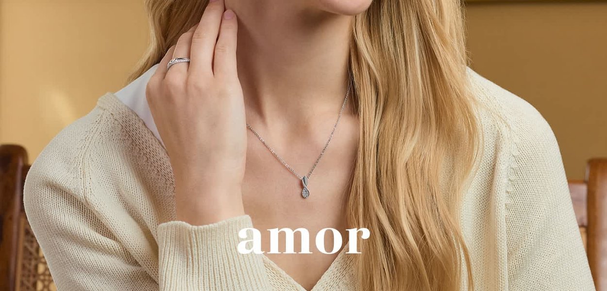 Collana di catena argentata con un pendente a goccia, caratterizzato da una superficie testurizzata. Chi la indossa ha capelli lunghi e sta indossando un maglione color crema.