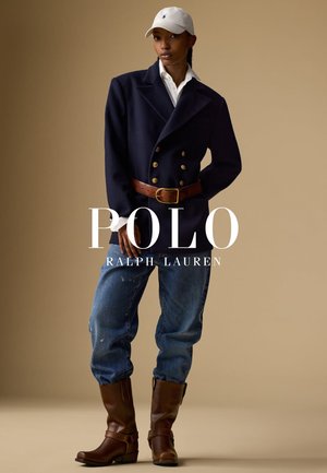 Marineblå dobbeltbrystet blazer, hvid skjorte med krave, slidte blå jeans og brune læderstøvler med spænder. Hvid kasket fuldender outfitet.