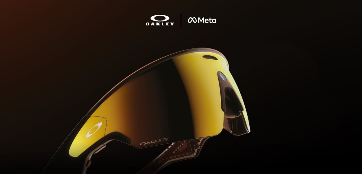 Occhiali da sole Oakley con una grande lente gialla curva, montatura trasparente e design elegante. Presentano i loghi Oakley e Meta sulla parte superiore.