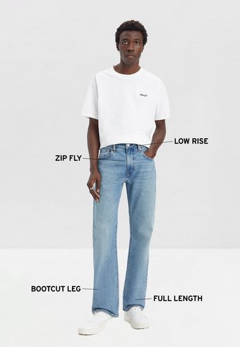 Camiseta blanca corta con el logo de "Levi's" combinada con jeans de corte bootcut en azul claro que presentan cierre con cremallera, tiro bajo y corte de largo completo.