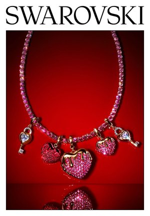 Roze kristallen ketting met hart- en sleutelbedeltjes, gouden accenten, glinsterend tegen een rode achtergrond, met het Swarovski-merklogo erboven.