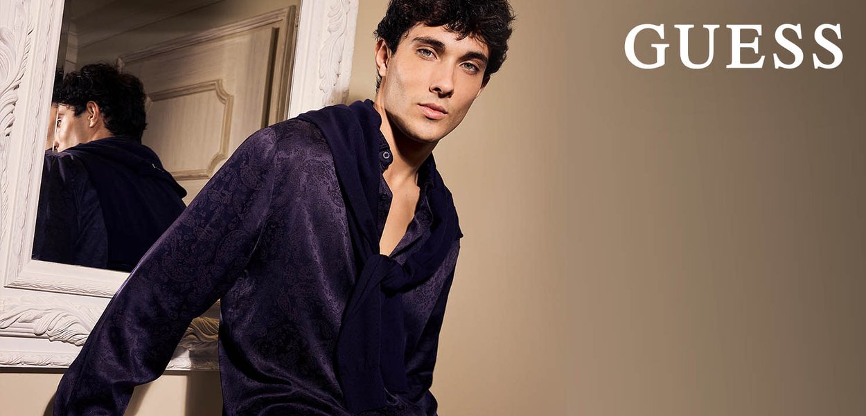 Camisa morada con un patrón y cuello, acompañada de una bufanda a juego, sobre un fondo neutro con un espejo decorativo.