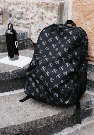 Schwarzer Rucksack mit einem sich wiederholenden grauen Logo-Muster. Hergestellt aus strapazierfähigem Material mit Netzseitentaschen und verstellbaren Trägern.