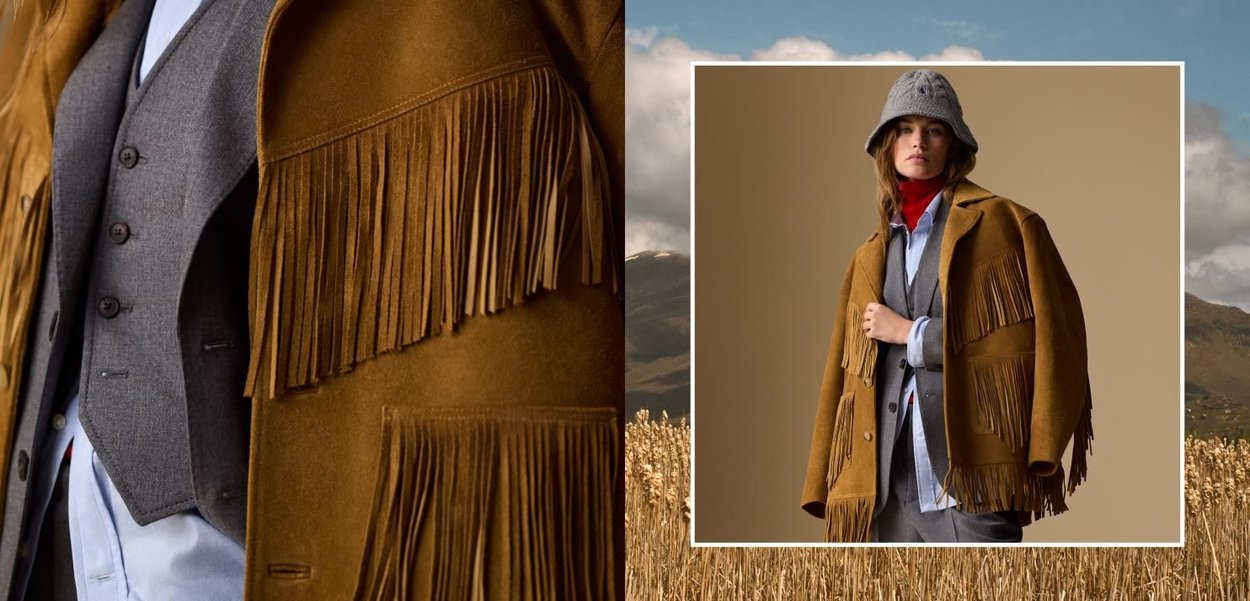 Kvinna som bär en brun fransad mockajacka, grå väst, ljusblå skjorta, röd polokrage och grå bucket-hatt mot en beige bakgrund.