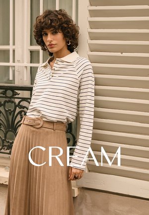 Gestreiftes, cremefarbenes Langarm-Poloshirt mit Kragen, kombiniert mit einem plissierten, beigen Rock mit Gürtel. Text „CREAM“ am unteren Rand.