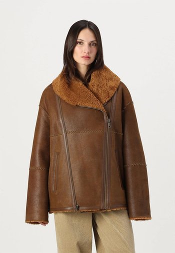 Bruine leren jas met een brede, tan shearling kraag, ritssluiting en schuin geplaatste voorzakken; beschikt over stikdetails en een relaxed fit.
