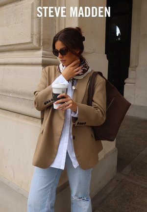 Beige blazer over een wit shirt, lichtblauwe ripped jeans, bruine tas, donkere zonnebril en een bruine sjaal met wit patroon. Koffiekop in de hand.