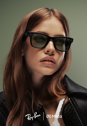 Lunettes de soleil Ray-Ban noires avec une monture carrée et des verres verts ; portées par une personne avec de longs cheveux bruns, sur un fond vert atténué.