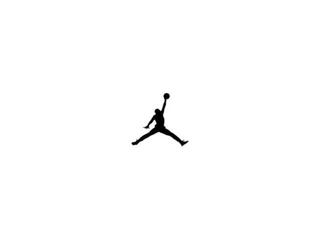 Silhouette d'une personne sautant, jambes écartées et un bras levé tenant un ballon de basket.