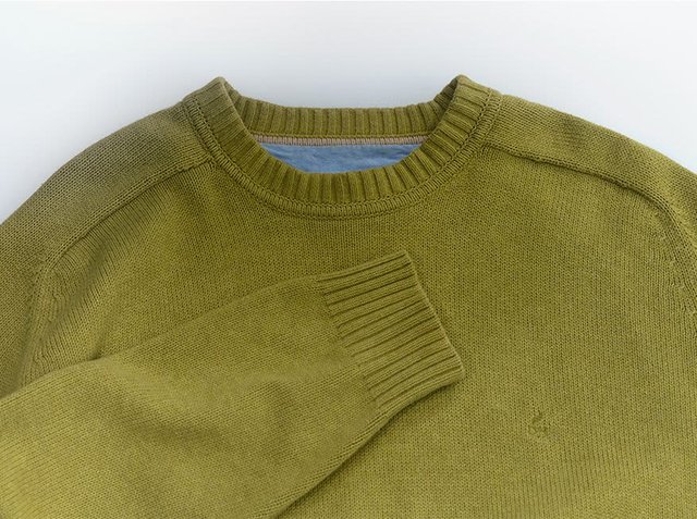 Olive green knitted sweater with a ribbed crew neckline and cuffs. Features a smooth texture and subtle logo on the front.