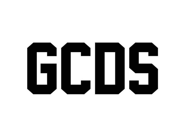 Zwarte vette letters die "GCDS" spellen op een witte achtergrond. De lettertype is geometrisch en modern, met scherpe hoeken en een uniforme dikte.