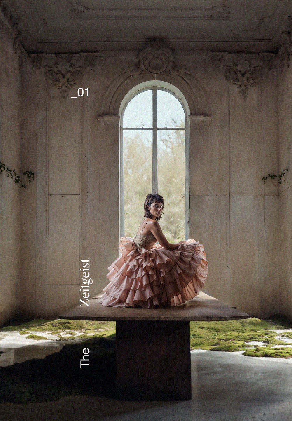 Layered, ruffled dress in light pink with a fitted bodice. Model seated on a rustic wooden table against an ornate, bright windowed backdrop.
