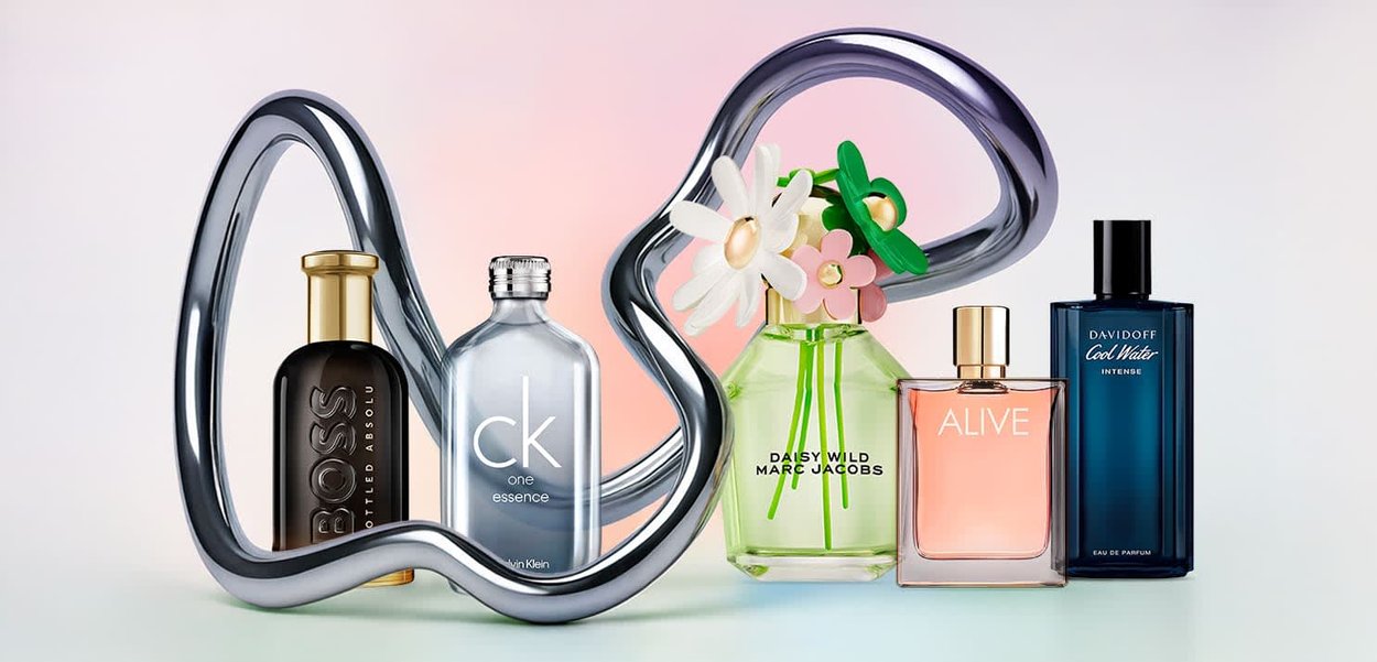 Samling af fem parfume flasker: sort glas med guldlåg, klart glas, grønt glas med blomsteraccents, pink glas og blåt glas. Sølvfarvet abstrakt stativ.