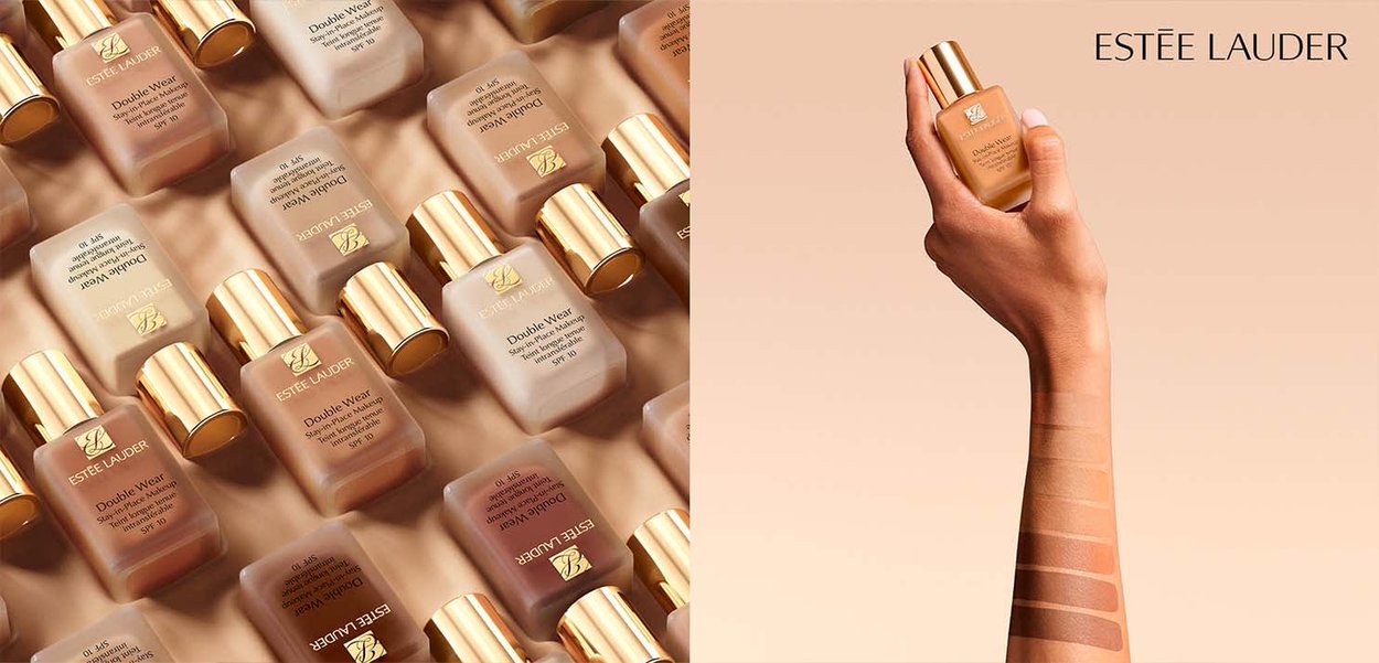 Estee Lauder Double Wear foundationflessen met gouden doppen, gepositioneerd in een raster. Een hand houdt een fles naast huidkleurstalen in verschillende tinten.