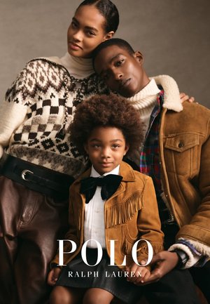 Tre persone posano insieme. La donna indossa un maglione lavorato a maglia con motivi. L'uomo ha una giacca di camoscio color beige. Il bambino indossa una giacca marrone con frange.