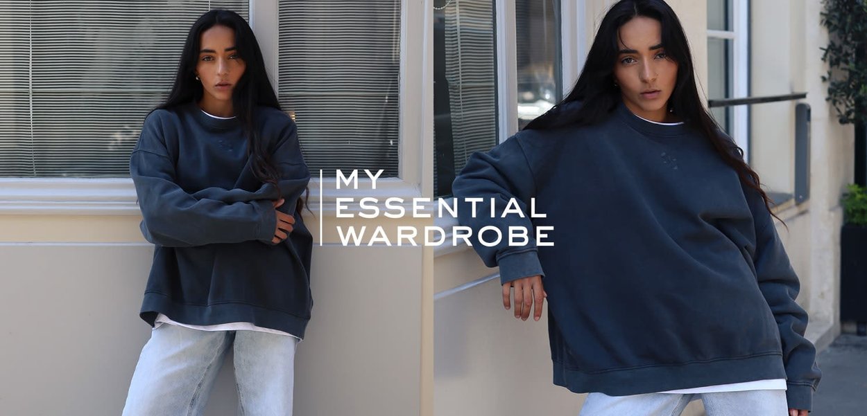 Felpa oversize grigio scuro con collo rotondo, realizzata in tessuto morbido. Abbinata a jeans blu chiaro, presentata in un contesto casual.
