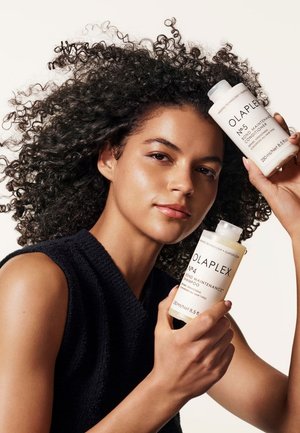 Shampoo Olaplex No. 4 e balsamo No. 5 in bottiglie di plastica trasparenti, con etichette contenenti testo nero, presentano una superficie liscia e tappi rotondi.