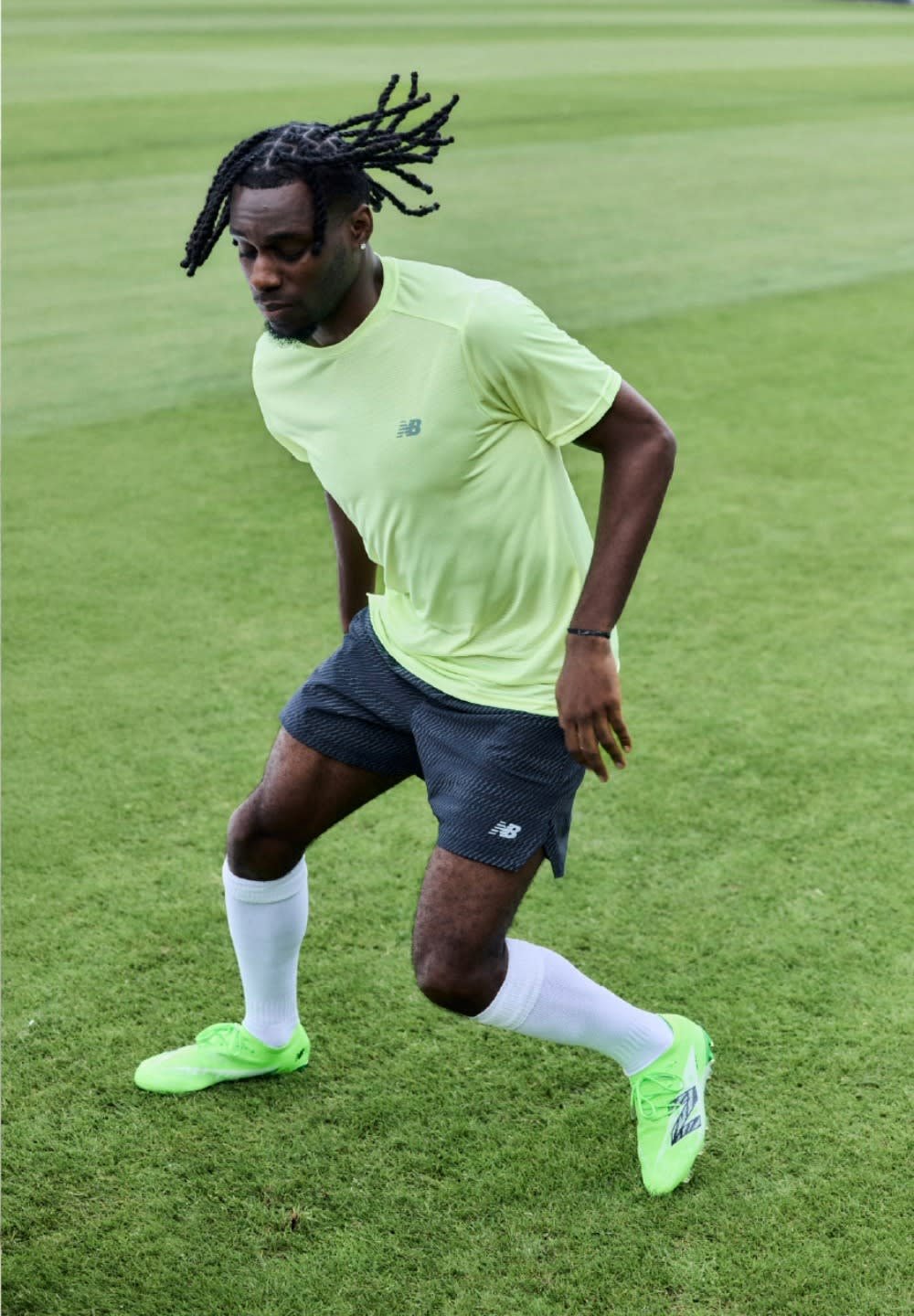 Des chaussures de sport vert vif, un short gris à motifs et un tee-shirt de sport jaune clair, portés lors d'une activité de course sur l'herbe.