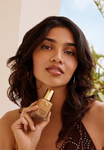 Flacone di fondotinta Estee Lauder Double Wear con tappo dorato, forma rettangolare, finitura opaca, tenuto da una persona con capelli medi e mossi.