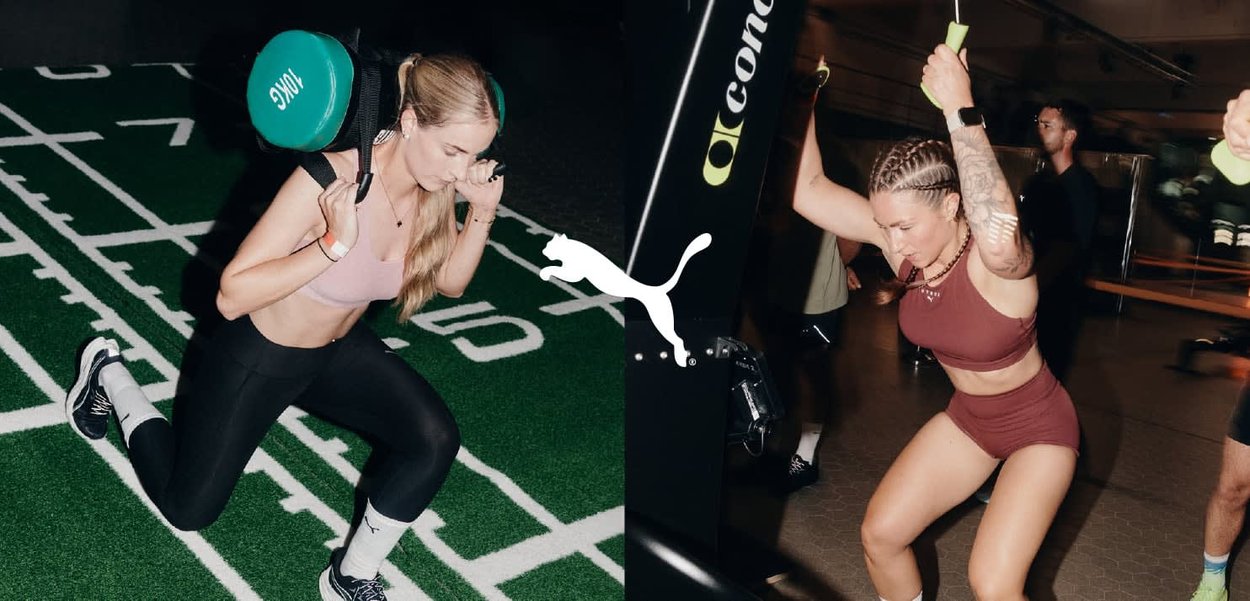 Dwie kobiety ćwiczą na siłowni. Jedna wykonuje wykrok z zielonym obciążeniem kettlebell; druga korzysta z maszyny do ćwiczeń na kabel. Obie mają na sobie odzież sportową.
