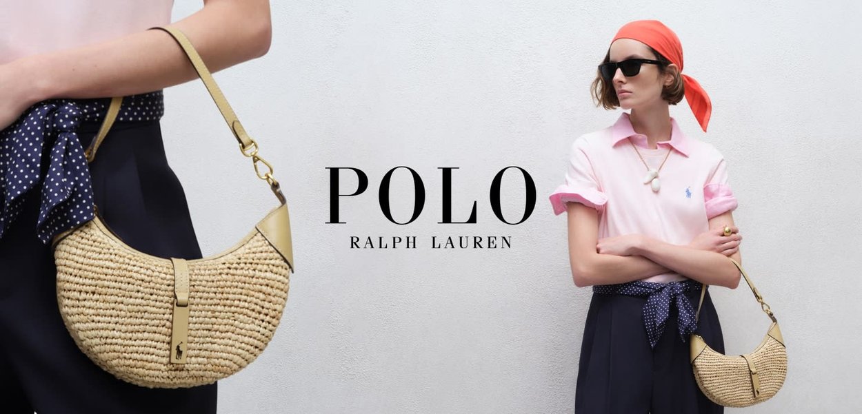 Mujer con camiseta polo rosa, pantalones oscuros, pañuelo rojo en la cabeza, gafas de sol y sosteniendo un bolso tejido de paja, posando frente a una pared lisa.