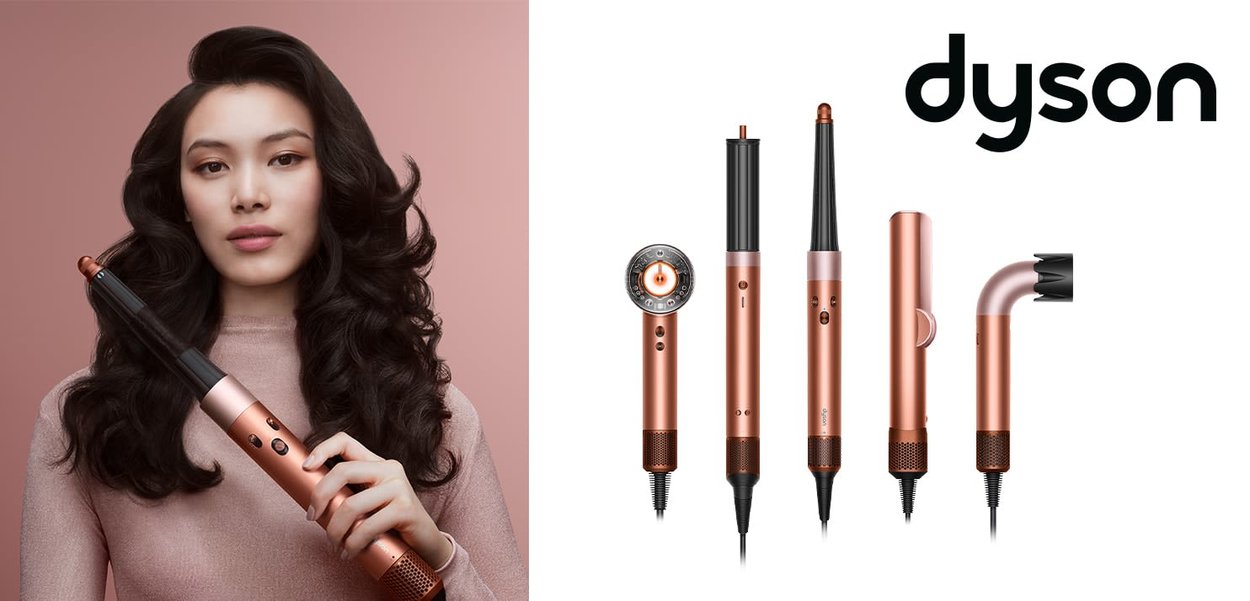 Il set di strumenti per lo styling dei capelli Dyson include un cilindro nero e rame, una spazzola e vari accessori caratterizzati da un design elegante e una presa texture.