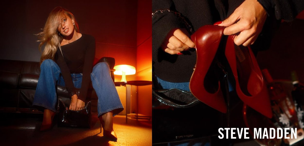 Rode hoge hakken met een slank ontwerp en een spitse neus, vastgehouden door een hand. Zwarte gepatineerde handtas op de schoot, spijkerdenim met flared broek, en warme verlichting.