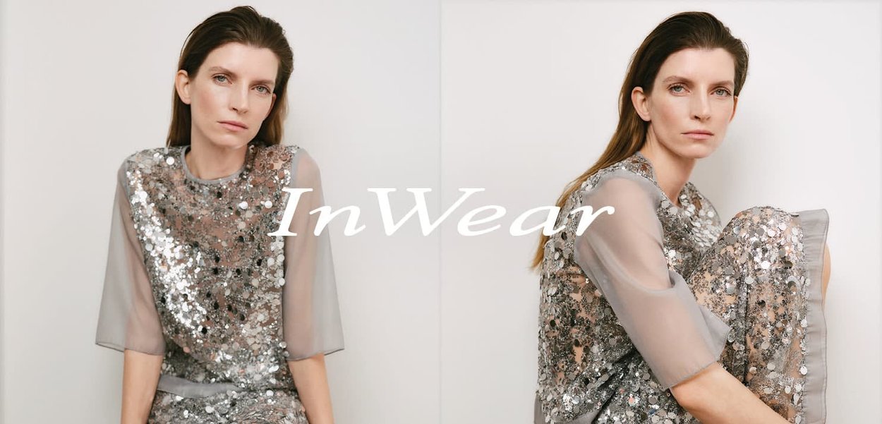 Graues Paillettenkleid mit transparenten Ärmeln, locker geschnitten und mit Rundhalsausschnitt. Weicher Stoff mit schimmernden Akzenten.