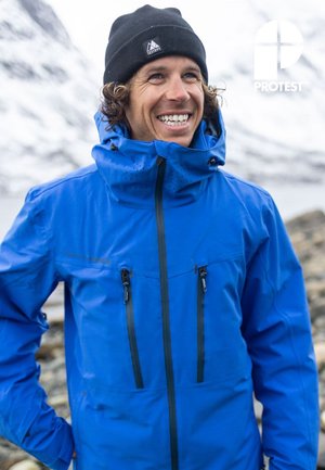 Blauwe waterdichte jas met zakken met rits en een hoge kraag. Heeft een gestructureerde afwerking en een bijpassende muts. Bergachtergrond.