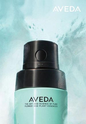 Aveda sprayflaske med svart dyse og hette, med en rund turkisbod. Teksten viser "AVEDA" og produktbeskrivelsen.