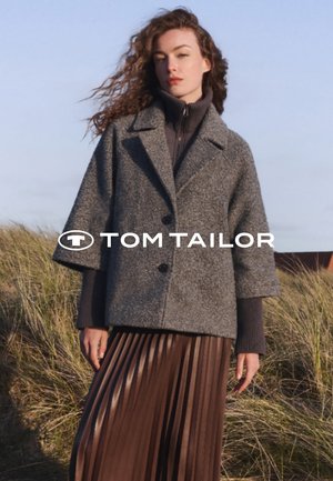 Graue Wollmischung Jacke mit weiten Ärmeln und zwei Knöpfen; kombiniert mit einem dunklen gerippten Rollkragenpullover und einem gefalteten braunen Rock.