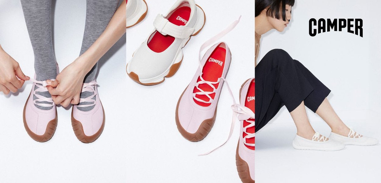 Persona che allaccia scarpe rosa con suole marroni accanto a sneakers Camper bianche e rosa, e una persona seduta che indossa scarpe bianche e pantaloni neri.