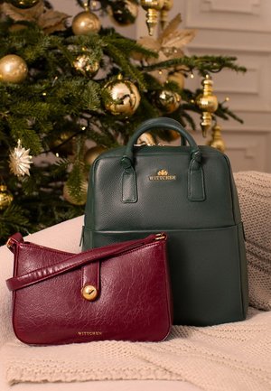 Green leather backpack with top handles, featuring gold logo. Burgundy leather crossbody bag with a gold button closure and adjustable strap.