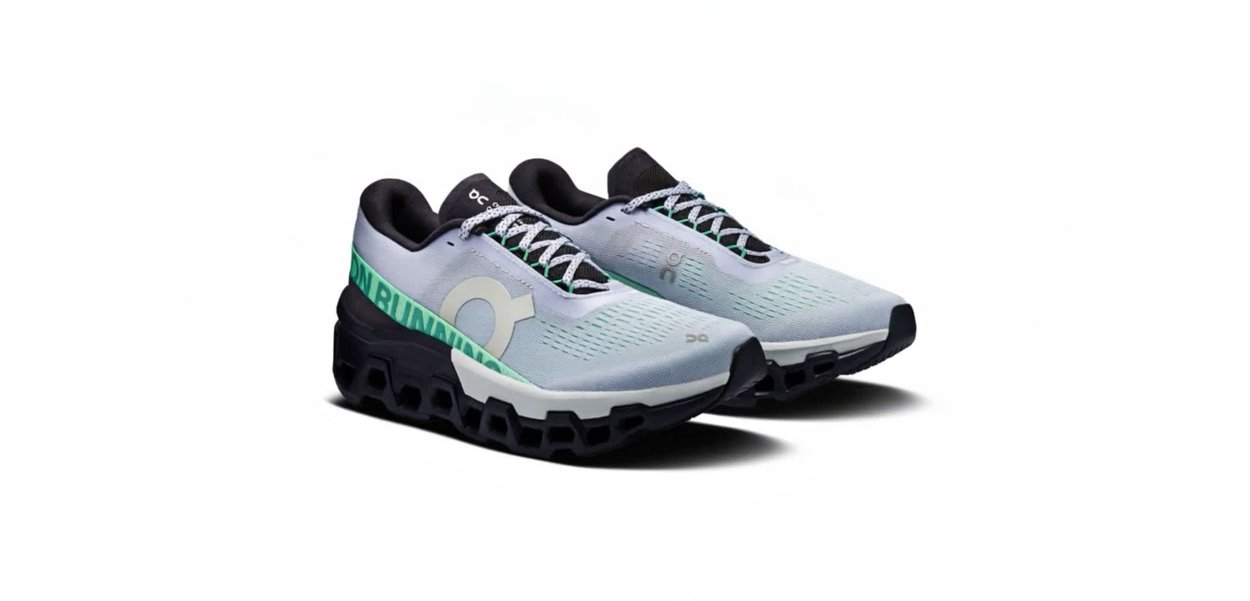 Lichtblauwe hardloopschoenen met een bovenwerk van mesh, zwarte accenten en een groen grafisch ontwerp. Voorzien van een dempende zool en een patroon op het loopvlak.