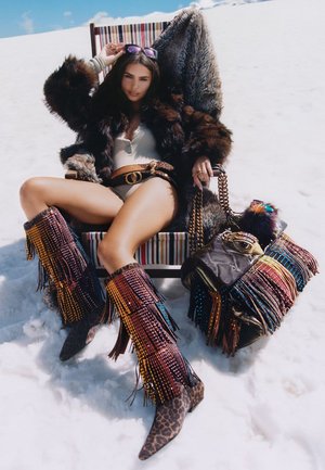 Brown faux fur jacket, silver belted bodysuit, multicolored beaded fringe boots, leopard-print accents, striped chair, textured handbag.