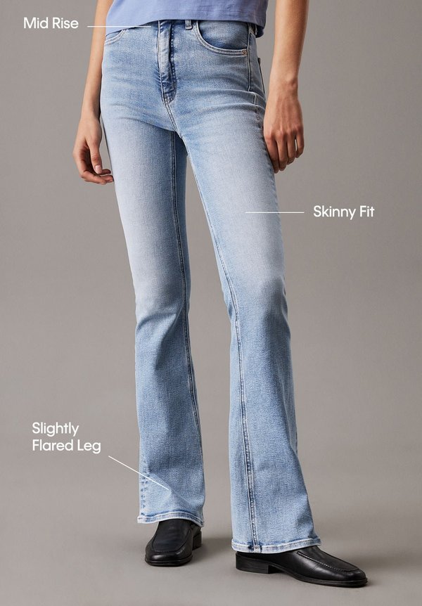 Jeans de denim azul claro con una altura media, corte ajustado y pierna ligeramente acampanada. Presenta una textura suave con costuras clásicas y bolsillos laterales.