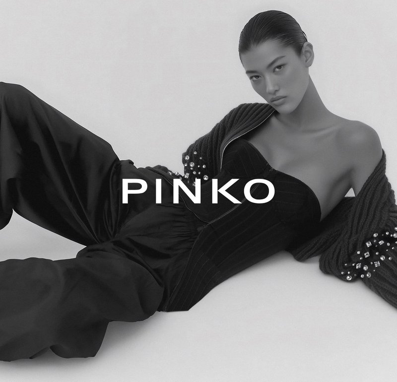 Zwart strapless bodysuit met verticale ribbels, gecombineerd met een donkergebreid vest met parelversieringen, op een neutrale achtergrond.