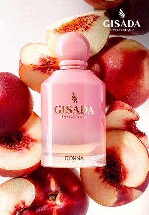 Flakon des Parfums Pink Gisada Donna, umgeben von ganzen und geschnittenen reifen Pfirsichen auf weißem Hintergrund.