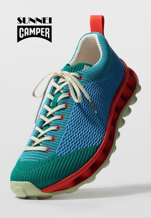 Baskets bleu et vert respirantes avec lacets blancs, œillets rouges et semelle d'amorti épaisse rouge avec semelle extérieure blanche texturée.