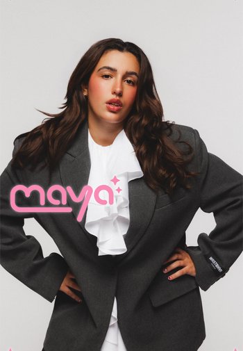 Blazer surdimensionné gris avec une blouse blanche à volants en dessous. Détails comprenant une fermeture à un bouton et le nom de la marque visible sur la manche.