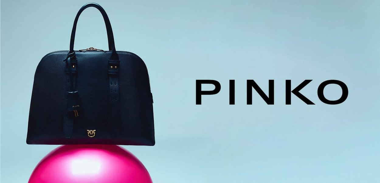 Czarna usztywniana torebka z podwójnymi górnymi uchwytami, zamkiem błyskawicznym, złotym logo i gładką fakturą, na jasnoniebieskim tle.