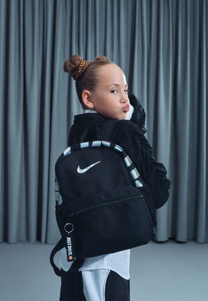 Sac à dos noir Nike avec un logo blanc, forme rectangulaire, bretelles ajustables et un détail coloré à motifs le long du haut. Compartiment zippé.