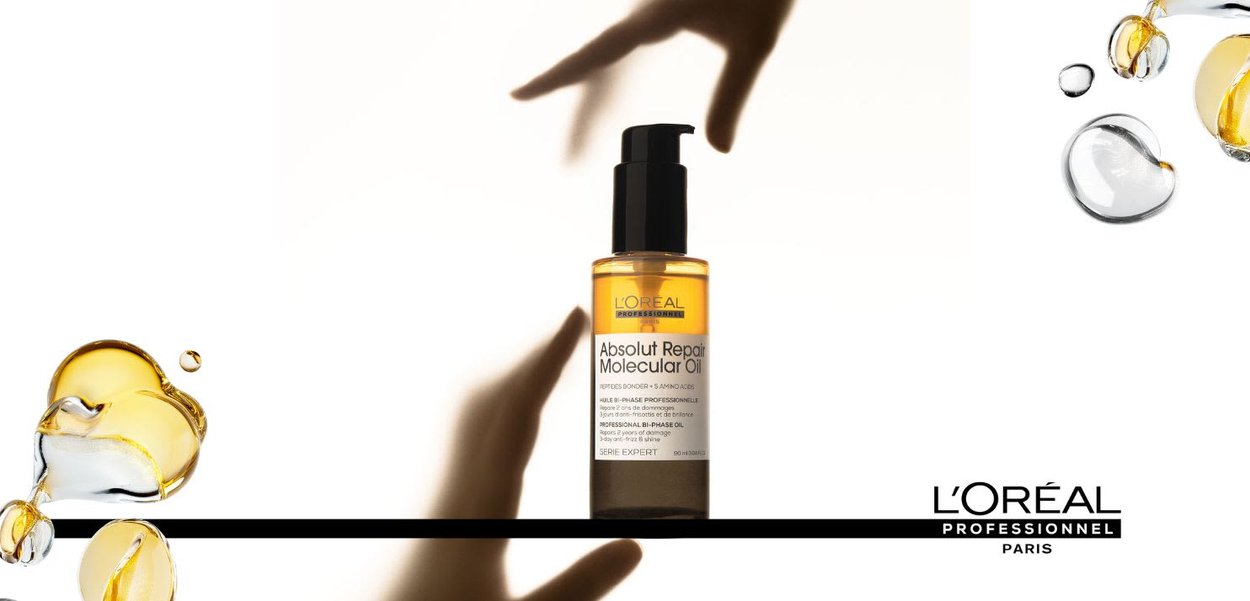 Olio per capelli L'Oréal Professionnel in una bottiglia trasparente; liquido dorato chiaro; tappo a pompa scuro; etichetta con testo in bianco e nero; design minimalista.