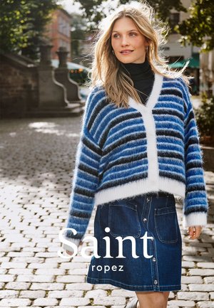 Blau-weiß gestreifter, flauschiger Cardigan über einem schwarzen Rollkragenpullover, kombiniert mit einem Jeansrock mit Vorderknöpfen und Seitentaschen.